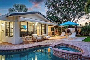 A modern house with a swimming pool, outdoor seating, and a view of the sky.