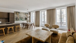 A modern living room with a dining area, large windows, and a view of the city.