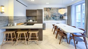 A modern kitchen with a central island, bar stools, and a dining table with chairs.
