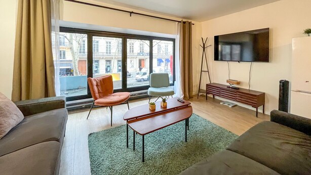 Una sala de estar moderna con un sofá, una mesa de centro, un televisor y vistas a la calle.
