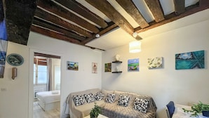 A room with a bed, a sofa with patterned cushions, a ceiling with exposed beams, and various wall art. - Urban Flat 192 - Charming flat - Basfour (París)