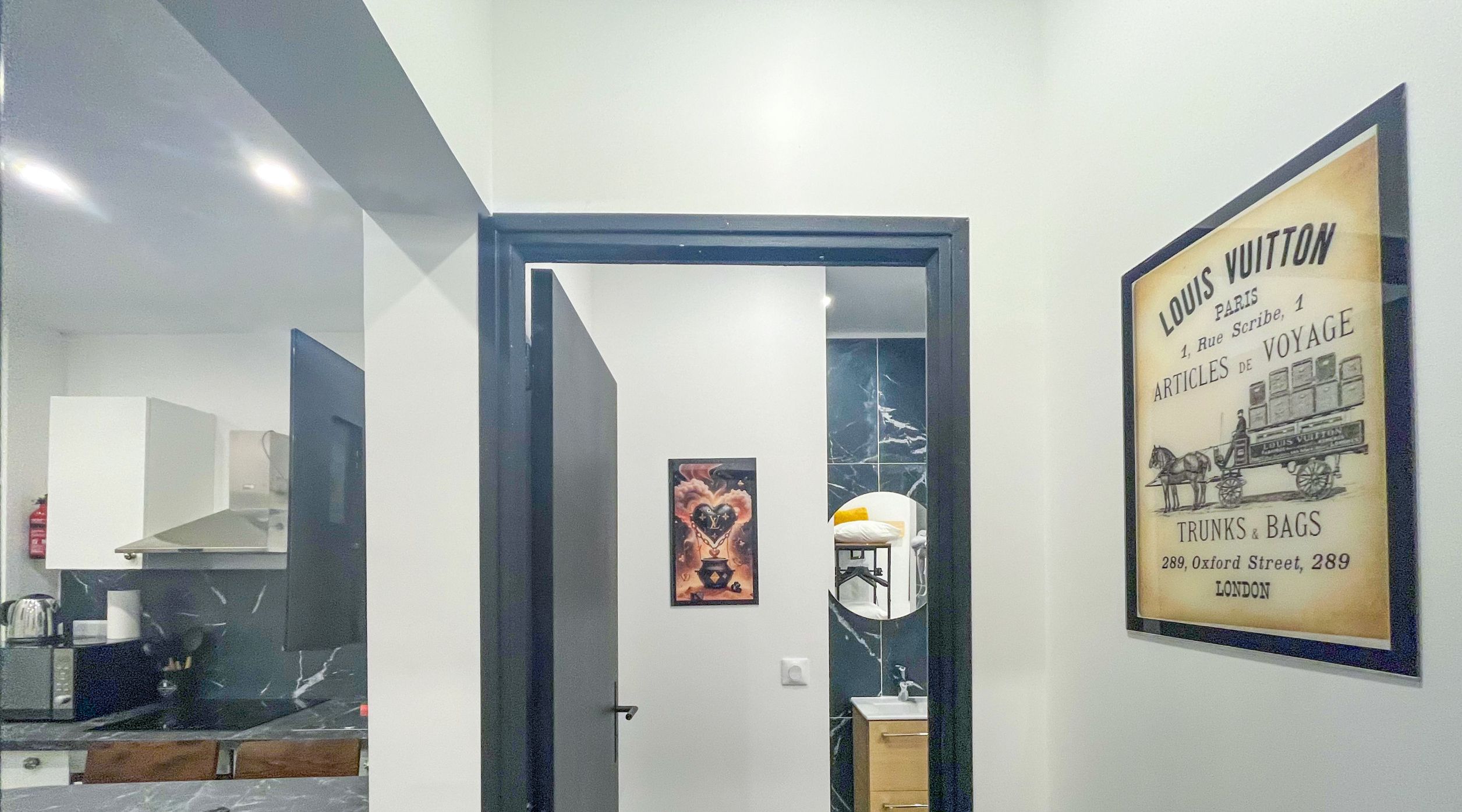 A modern interior with a kitchen, a bathroom with a mirror, and a door leading to another room.