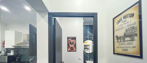 A modern interior with a kitchen, a bathroom with a mirror, and a door leading to another room.