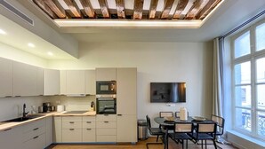 Eine moderne Küche mit eingebauten Geräten, ein Essbereich mit Tisch und Stühlen sowie ein großes Fenster für natürliches Licht.
