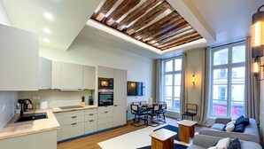 Eine moderne Küche mit weißen Schränken, ein Essbereich mit Tisch und Stühlen sowie eine gemütliche Sitzecke mit Sofa und Sesseln.