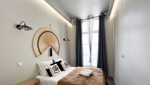 Ein modernes Schlafzimmer mit Bett, Wandventilator und einem Vorhangfenster.