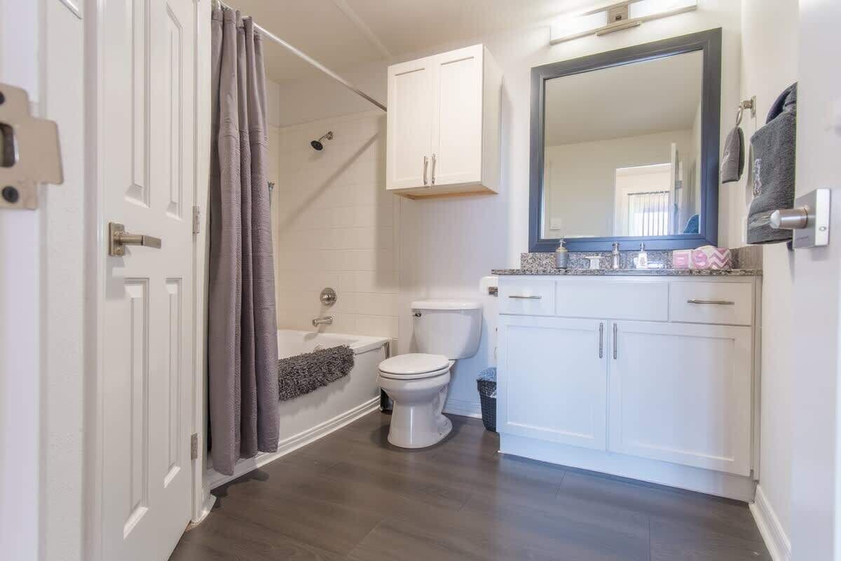 Een badkamer met bad, toilet en wastafel met spiegel.