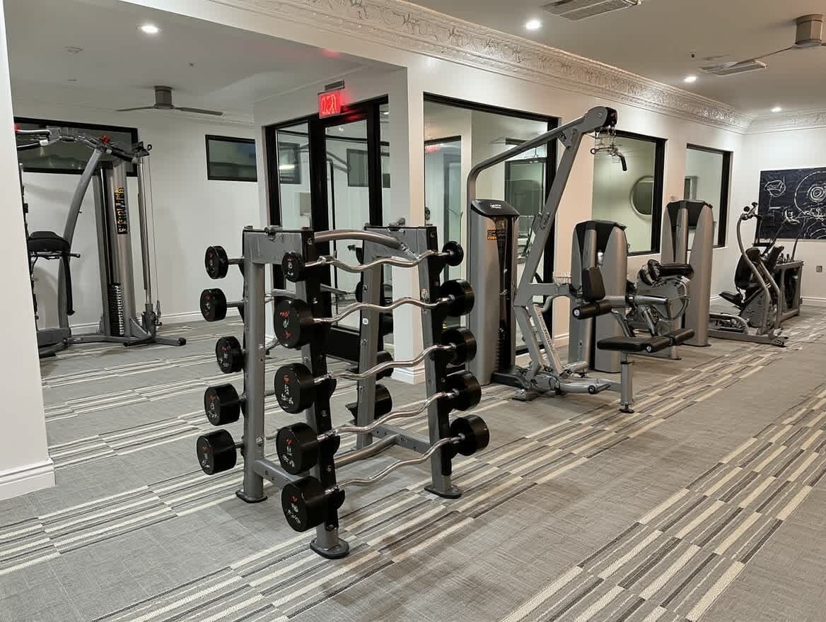 Een sportschool met gewichthefapparatuur, spiegels en fitnessapparaten.