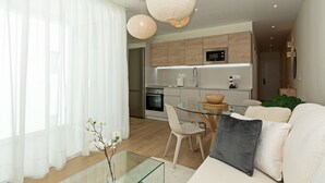 Une cuisine moderne avec des meubles en bois, une table à manger en verre et un canapé blanc dans l’espace salon.