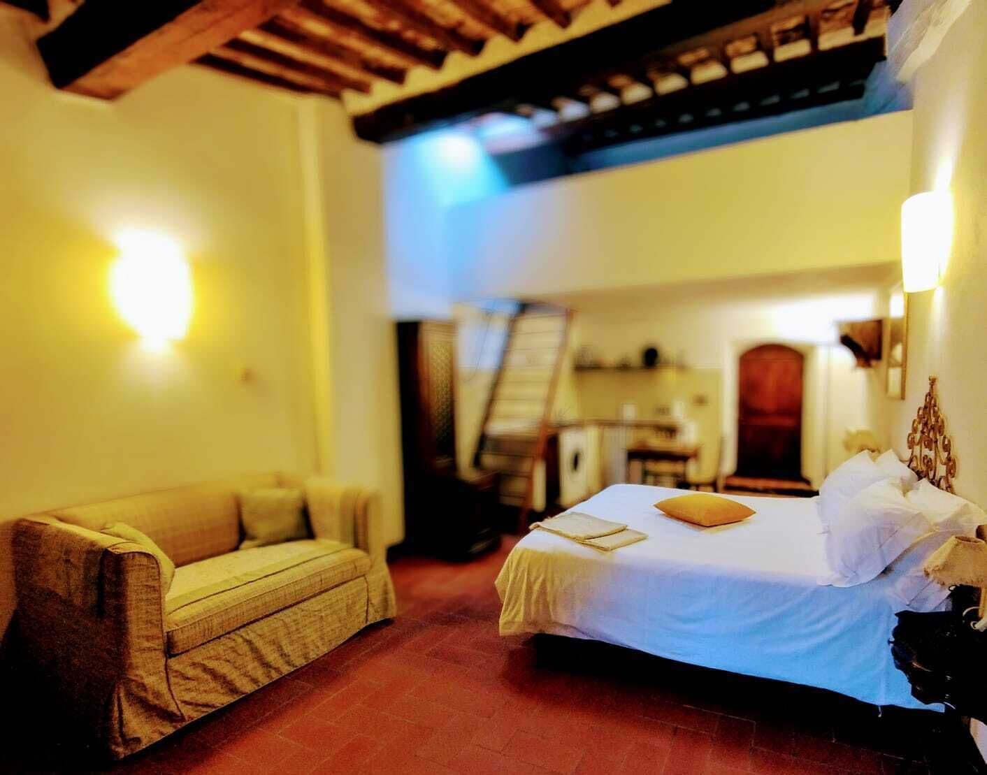 A cozy room with a bed, a sofa, and a staircase leading to an upper level.