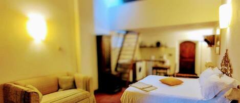A cozy room with a bed, a sofa, and a staircase leading to an upper level.