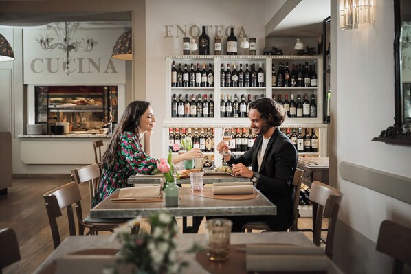 A restaurant interior with a bar area displaying numerous wine bottles. - L'Orto delle Terme (San Quirico d'Orcia)