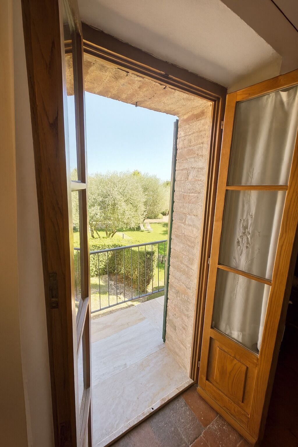 A wooden door with a glass panel leading to a balcony with a metal railing.