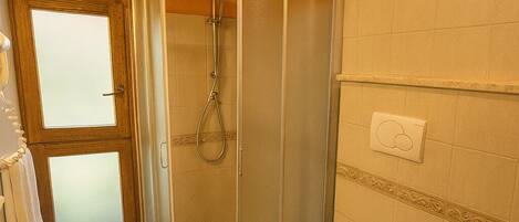 A bathroom with a glass-enclosed shower, a toilet, a sink, and a bidet.