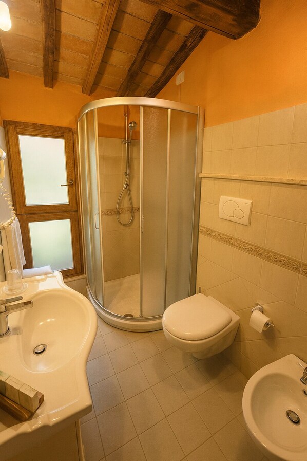 A bathroom with a glass-enclosed shower, a toilet, a sink, and a bidet. - L'Orto delle Terme (San Quirico d'Orcia)