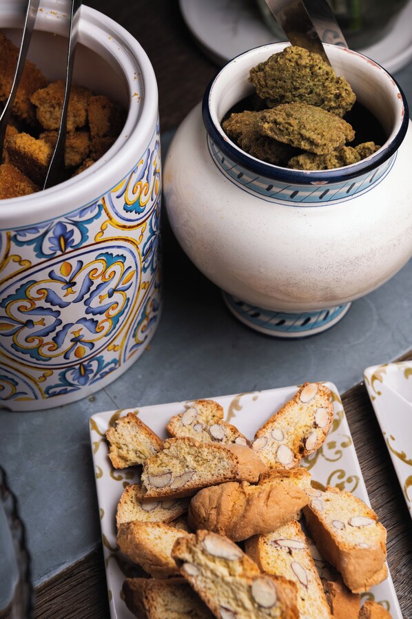 A table with a plate of almond-topped pastries and two decorative bowls. - L'Orto delle Terme (San Quirico d'Orcia)