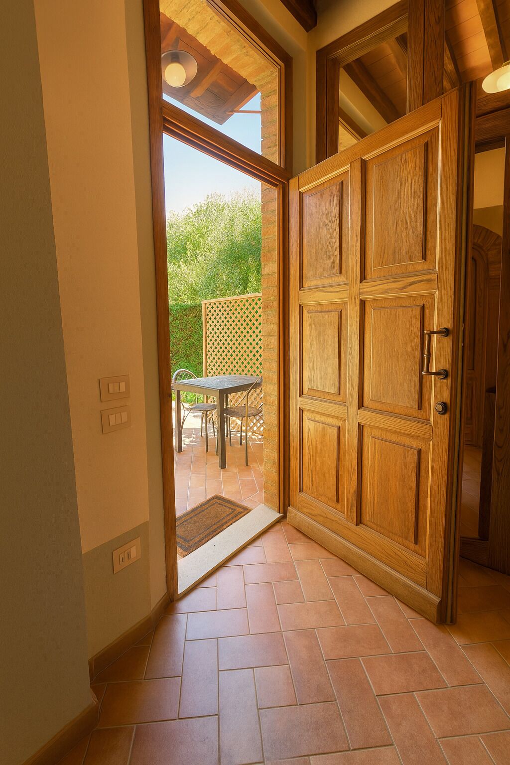A wooden door with a glass panel, leading to an outdoor patio with a table and chairs.