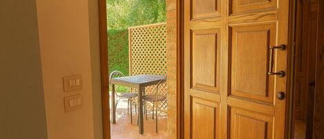 A wooden door with a glass panel, leading to an outdoor patio with a table and chairs.