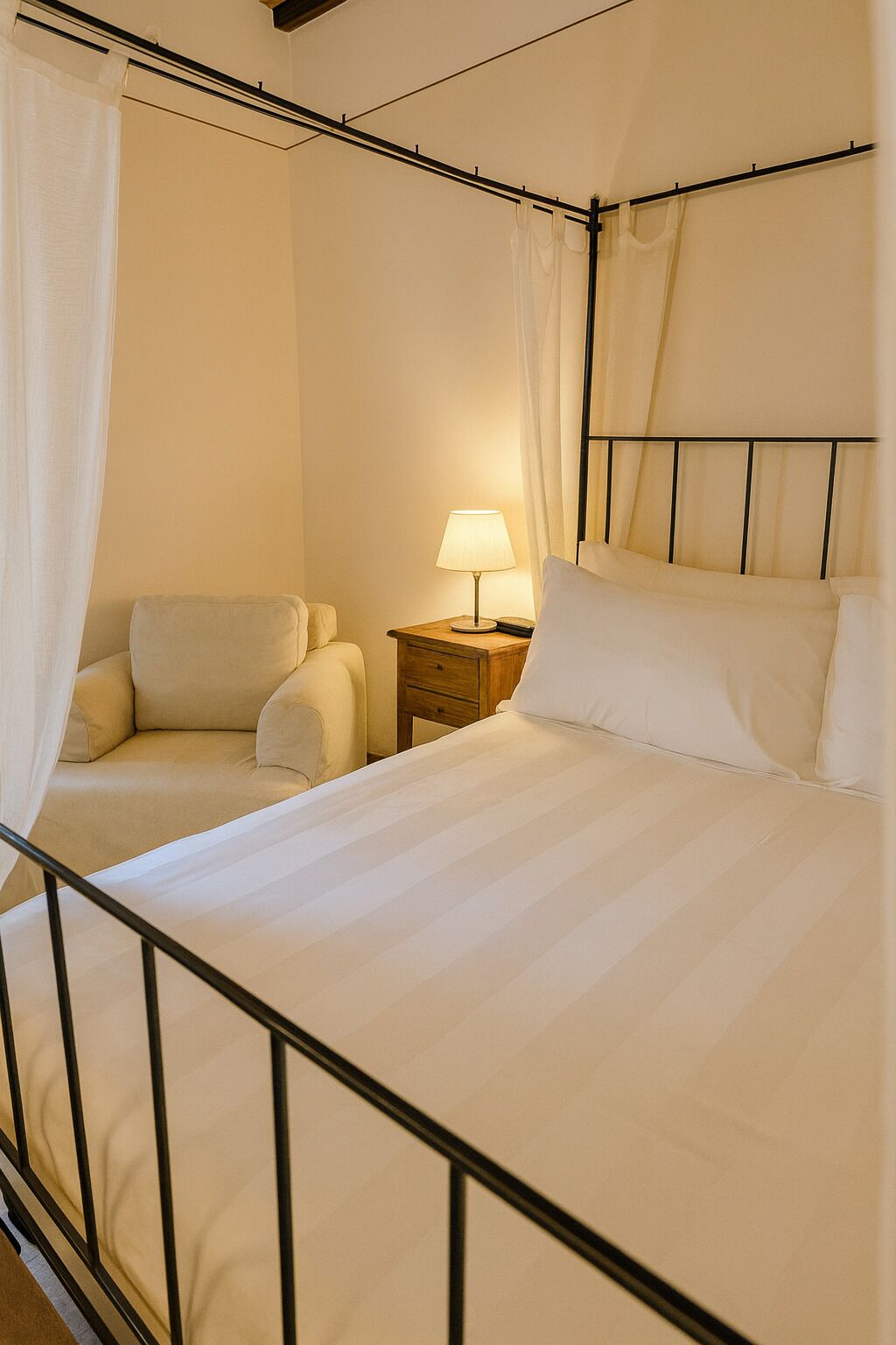 A neatly arranged bedroom with a bed, a nightstand with a lamp, and a chair.