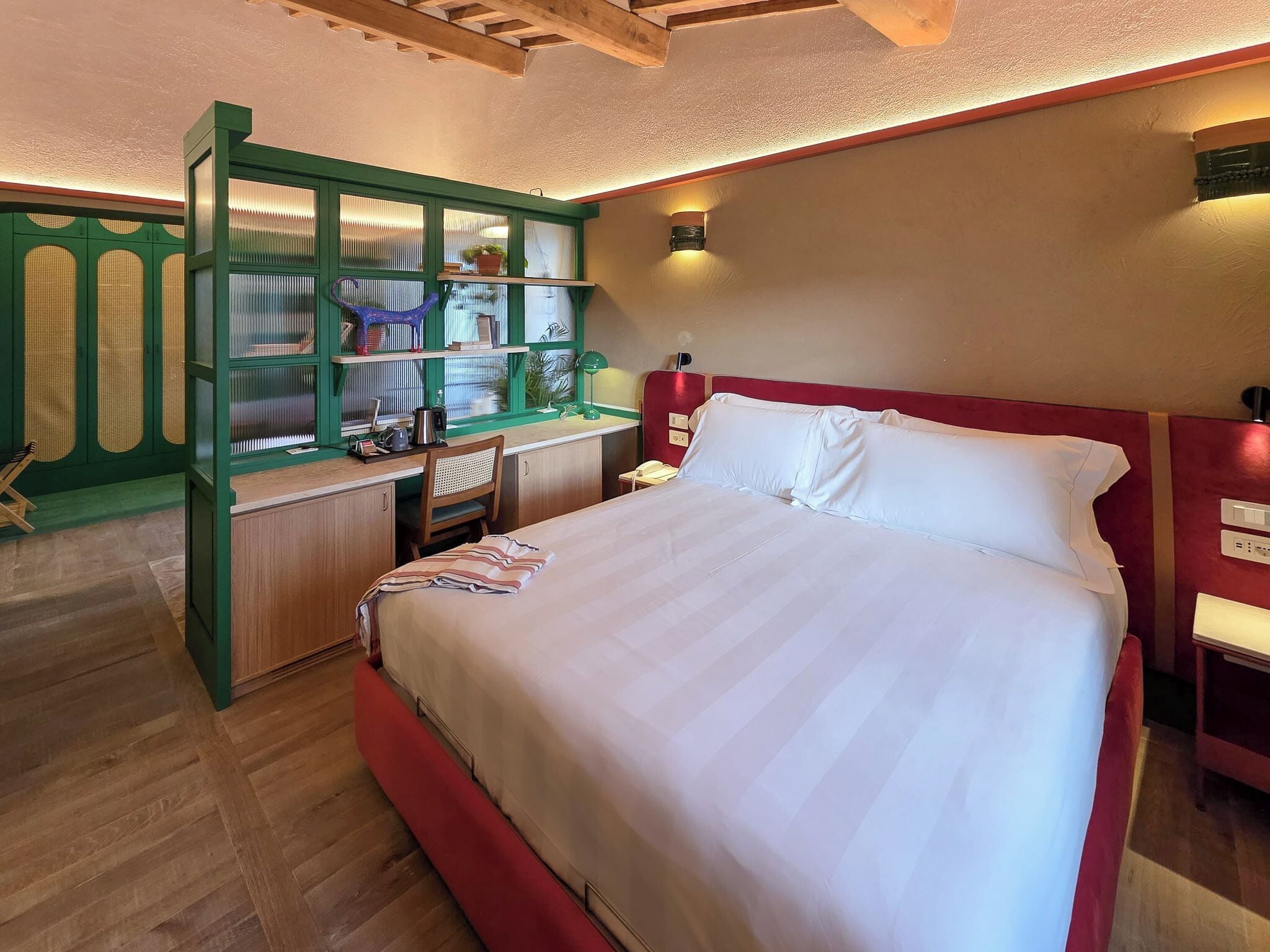 Un dormitorio con una cama grande, un escritorio con silla y un armario verde con estantes.