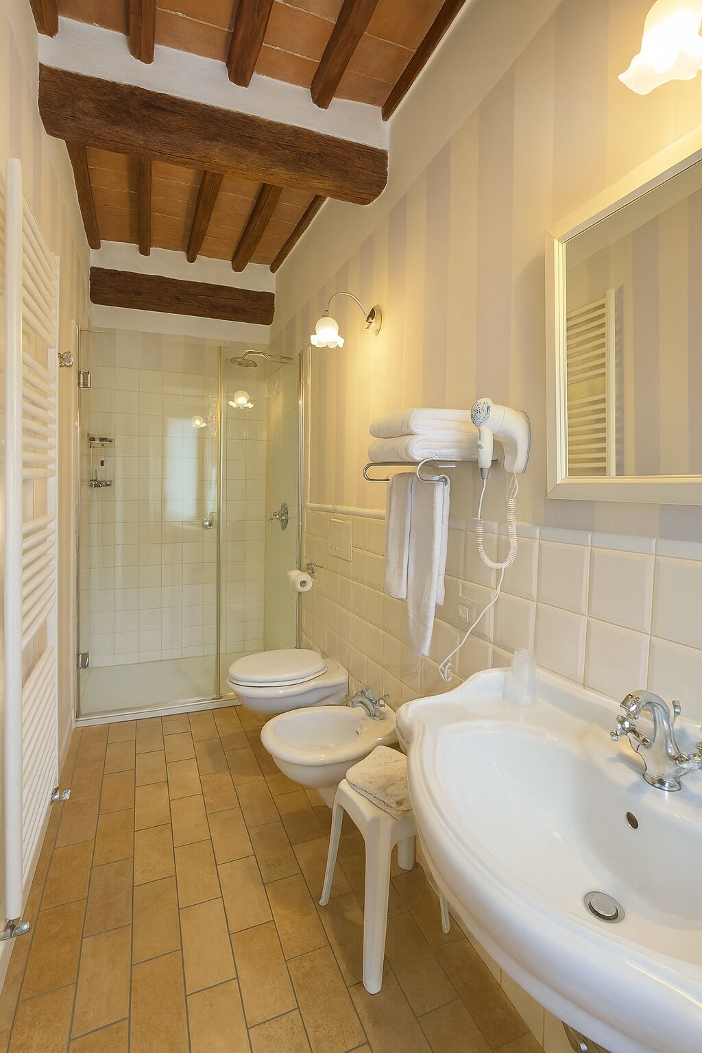A bathroom with a shower, toilet, bidet, and sink.