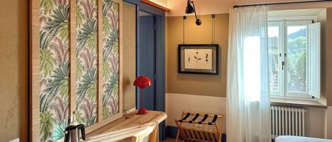 A cozy room with a wooden table, a red lamp, and a framed botanical print on the wall.