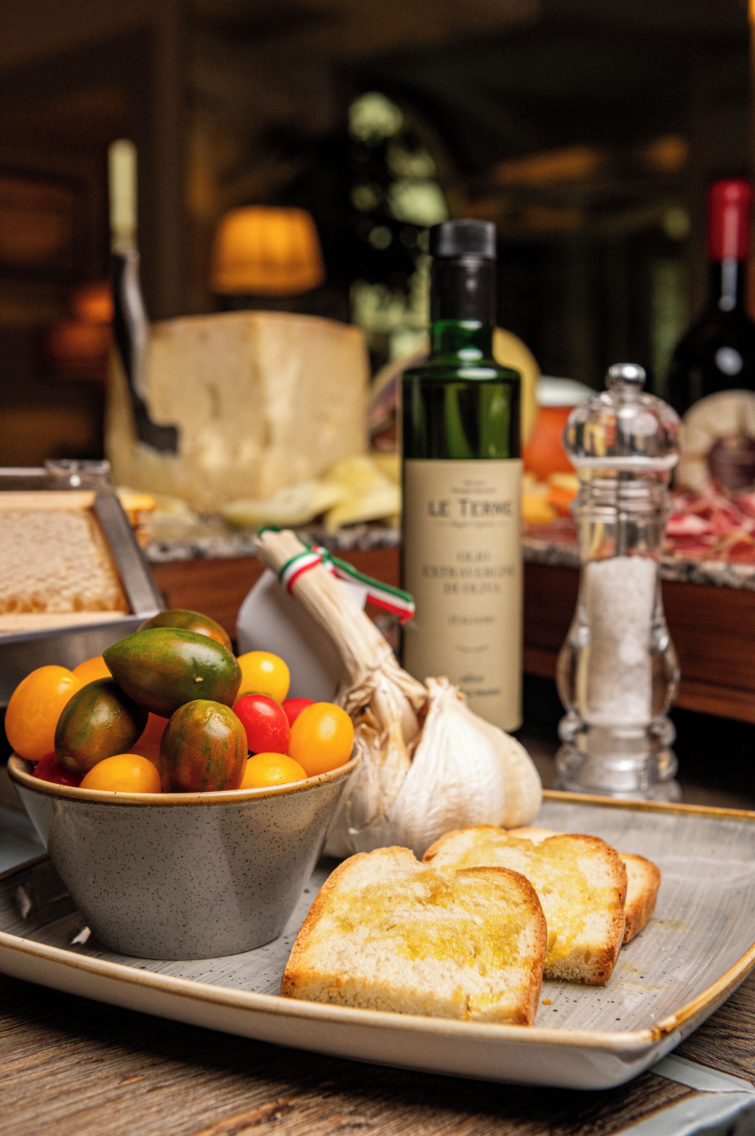 A tray with bread, a bowl of fruit, a bottle of wine, and a salt shaker.