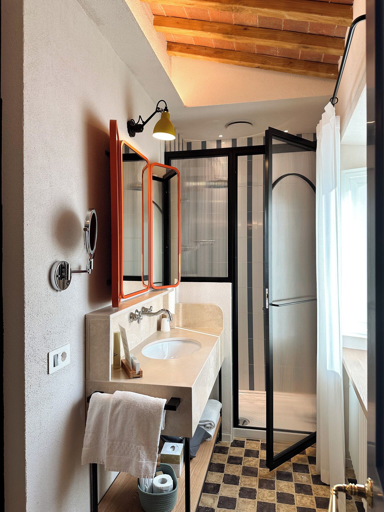 Une salle de bain moderne avec un grand miroir, un lavabo et une cabine de douche.