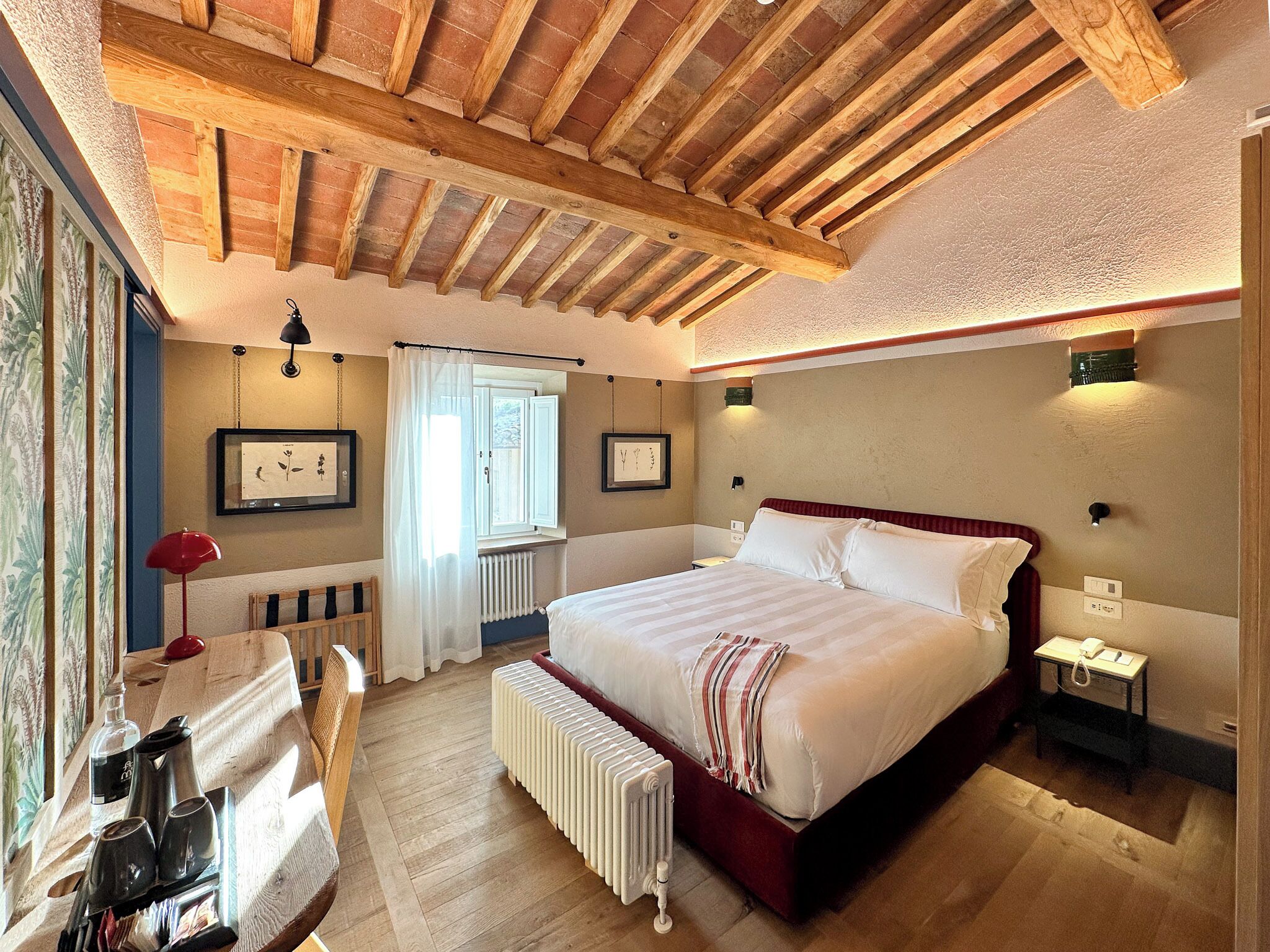 Ein Schlafzimmer mit einem großen Bett, einem Schreibtisch mit Stuhl, einem Heizkörper und einem Fenster mit Vorhängen.
