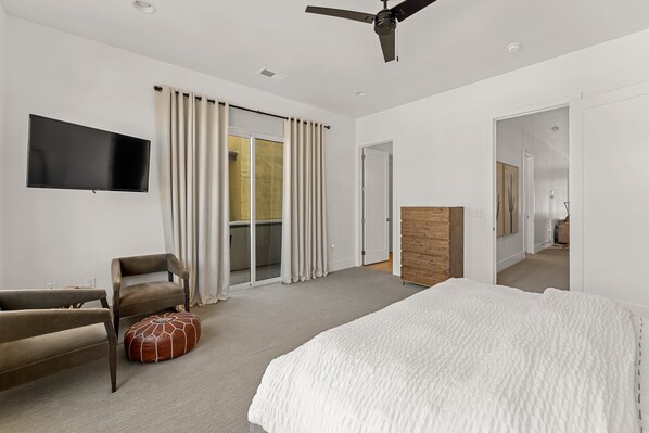 Une chambre d’hôtel moderne dotée d’un grand lit, d’un téléviseur à écran plat, d’un canapé et d’une porte-fenêtre coulissante donnant sur un balcon.