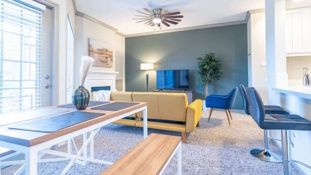 A modern living room with a sofa, a coffee table, a TV, and a ceiling fan. - Boulevard Stays Peaceful 1BR King Suite Pool, Parking Gym 02 (Austin)
