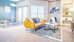 A modern living room with a yellow sofa, a round coffee table, and a striped rug. - Boulevard Stays Tranquil 1BR King Suite Pool, Parking Gym 04 (Austin)