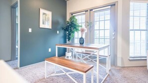 A room with a dark blue wall, a white-framed table with a bench, a potted plant, and a framed picture. - Boulevard Stays Tranquil 1BR King Suite Pool, Parking Gym 04 (Austin)