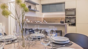 A modern dining area with a wooden table set for a meal, surrounded by chairs. - Casa Lenora by Varenna Holidays (Bellano)