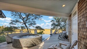 A wooden deck with a hot tub, lounge chairs, and a view of the landscape. - Beauitful marsh front, six bedroom home with infinity pool with hot tub. (Bald Head Island)