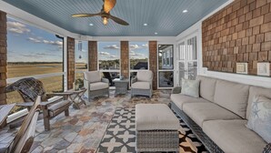 A covered outdoor area with wicker furniture, a ceiling fan, and a patterned floor. - Beauitful marsh front, six bedroom home with infinity pool with hot tub. (Bald Head Island)