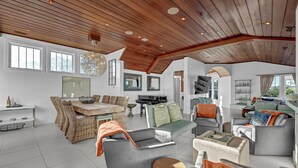 A spacious living room with a high ceiling, a dining area, and a piano. - Beauitful marsh front, six bedroom home with infinity pool with hot tub. (Bald Head Island)