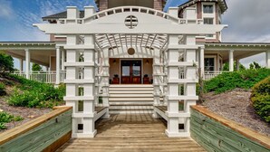 A grand entrance with a white archway leading to a wooden deck. - Five bedroom home on Bald Head Island's East Beach, make your next island getawa (Bald Head Island)
