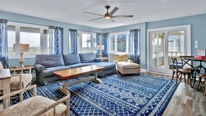A living room with a blue patterned rug, a sofa, a coffee table, and a ceiling fan. - Incredible ocean views from Sand Castle on Bald Head Island (Bald Head Island)