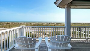 A wooden deck with two white Adirondack chairs facing a beach. - Incredible ocean views from Sand Castle on Bald Head Island (Bald Head Island)