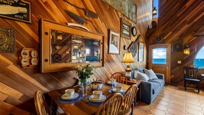 A wooden interior with a dining area, a sofa, and a view of the ocean. - 3965 Marine Gardens - Oceanfront with Bay Views (Pacific Grove)