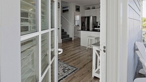 Een moderne keuken met witte kasten, een roestvrijstalen koelkast en een klein eiland met een wit aanrecht.