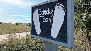 Een bord met een voetafdruk ontwerp en de tekst 'Sandy Toes'.