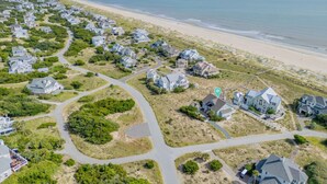 An aerial view of a coastal residential area with houses, roads, and a beach. - Oceanfront, 4 Bedrooms, BHI (Bald Head Island)