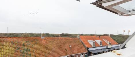 A view from a window overlooking a building with a red-tiled roof and a flat facade.