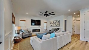 Ein Wohnzimmer mit einer Couch, einem Kamin, einem Fernseher und einem Deckenventilator.