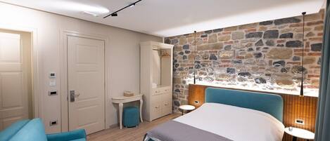 A bedroom with a stone wall, a bed, a desk, and a chair.
