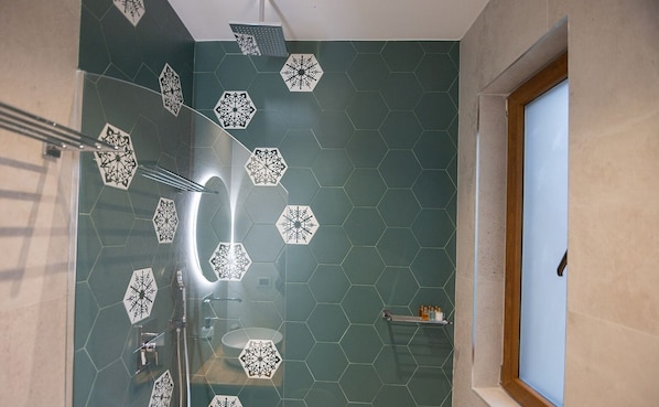 A bathroom with hexagonal patterned tiles, a glass shower enclosure, and a wooden-framed window. - Moonlight Serenade (Korçë)
