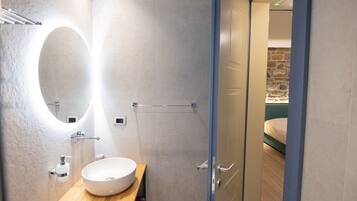 Un baño moderno con un espejo ovalado grande, un lavamanos blanco y un perchero para toallas.