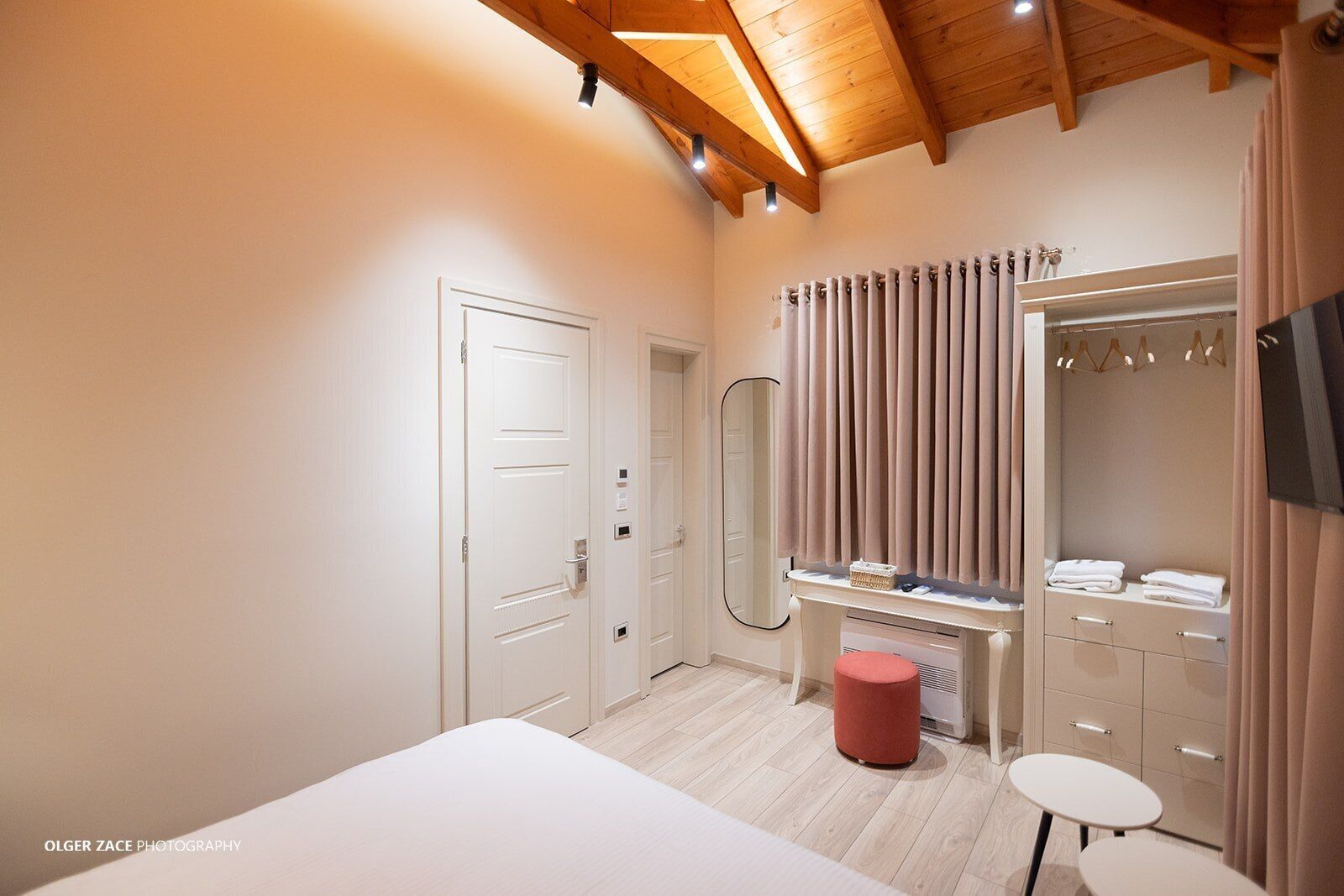 Una camera da letto con un letto, una toeletta con uno specchio, un termosifone e uno sgabello rosso.